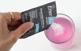 Woman pouring an Ener-C Sport electrolyte drink mix packet into her lemonade