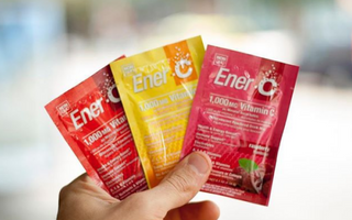 Holding Ener-C's flavour packets of Tangerine Grapefruit Vitamin C, Peach Mango Vitamin C, and Raspberry Vitamin C drink mix