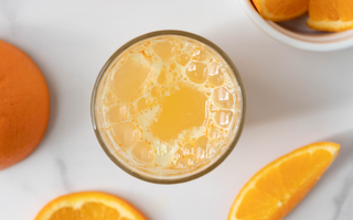 An orange mango ener-c mixed vitamin c drink surrounded by diced orange slices